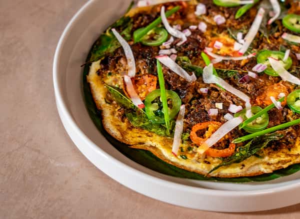 Flatbread topped with spiced meat, fresh herbs, and vegetables served at an upscale modern Indian restaurant