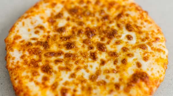 Round garlic cheese bread with melted, browned cheese on a red background.