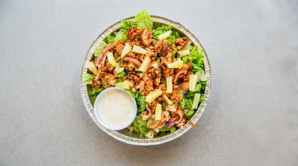 Chicken salad with pineapple and a side of dressing in a foil container