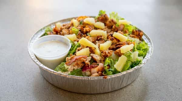 Chicken salad with pineapple and a side of dressing in a foil container