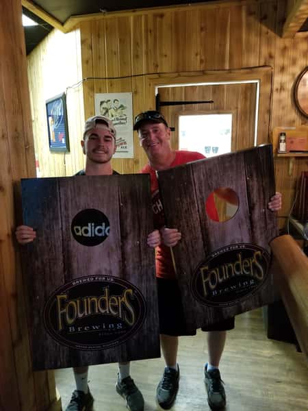 men holding cornhole boards