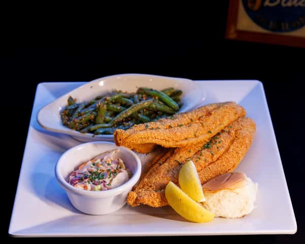 Neil St. Blues' Signature large fried catfish dinner served with sautéed garlic green beans, coleslaw, and dinner rolls.
