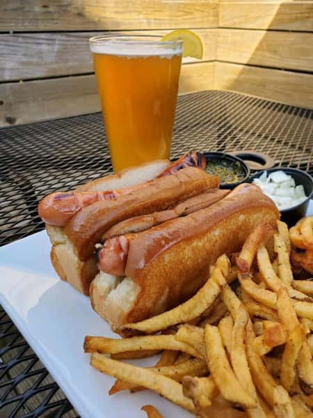 two hotdogs with a side of fries and a glass of beer