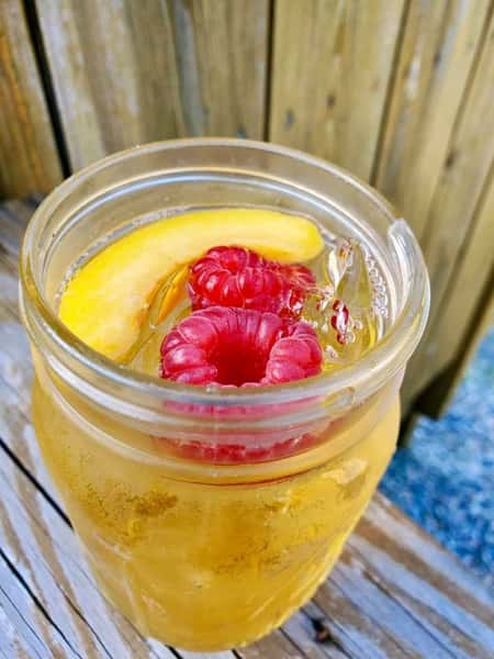 cocktail with raspberries and a mango wedge