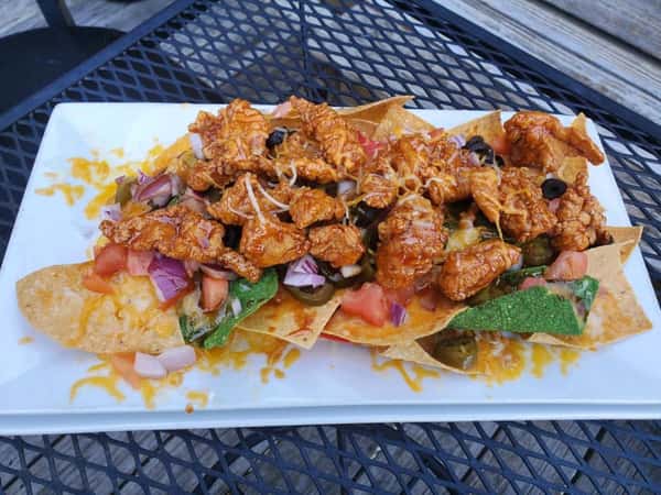 nachos topped with chicken, beans, red onion, and cheese