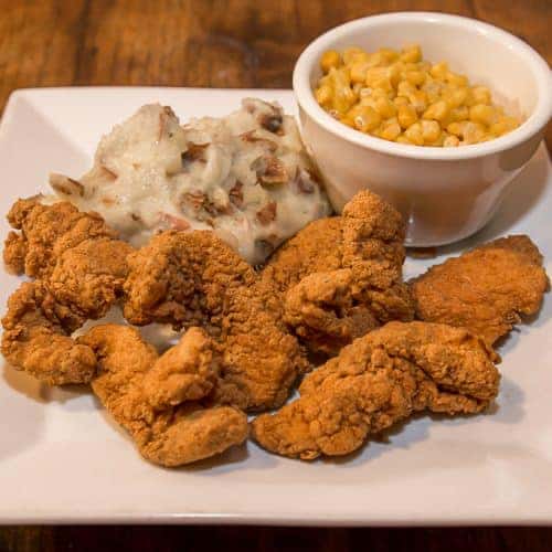 fried chicken strips with mashed potatoes and a side of corn