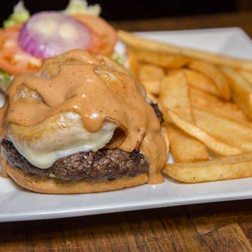 cheeseburger topped with sauce with a side of fries