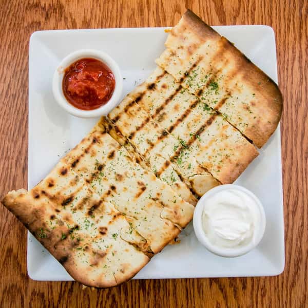 Grilled flatbread slices with parsley, served on a white plate with salsa and sour cream.