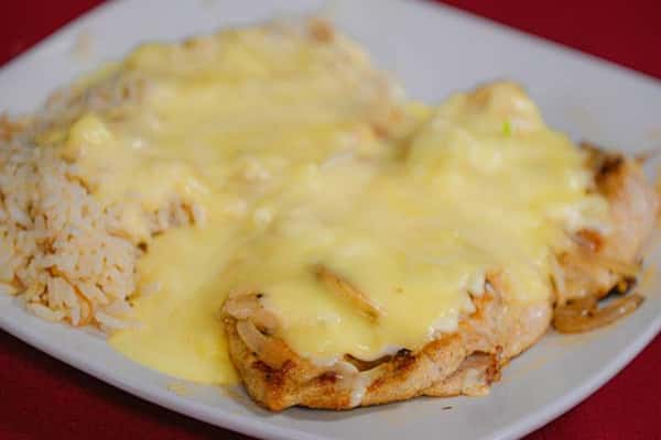 Smothered chicken breasts topped with melted cheese and served with seasoned rice
