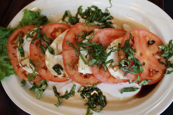 Caprese salad with sliced tomatoes, fresh mozzarella, basil, and balsamic glaze