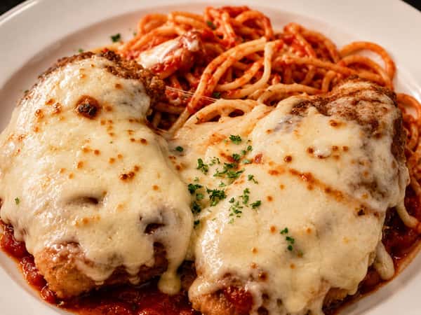 Veal Parmesan topped with tomato sauce and melted cheese and served with spaghetti