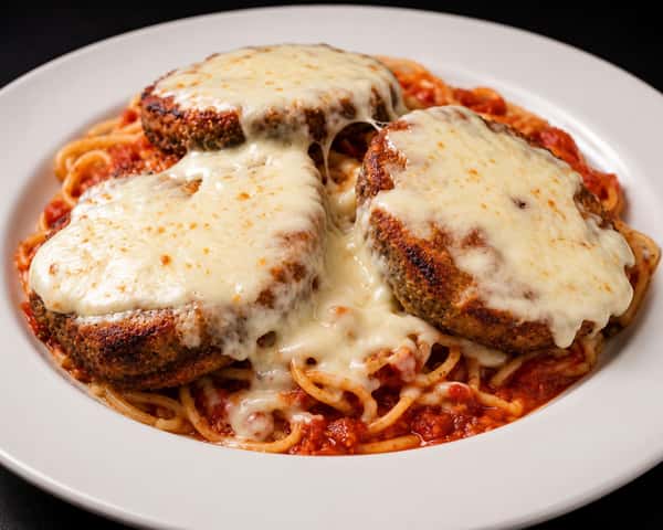 Eggplant Parmesan topped with melted cheese and served with spaghetti