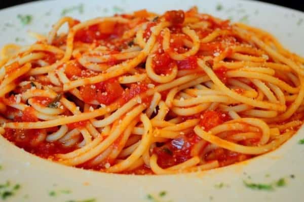 Spaghetti tossed in tomato sauce with sliced vegetables