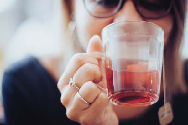 Woman drinking tea from a clear mug
