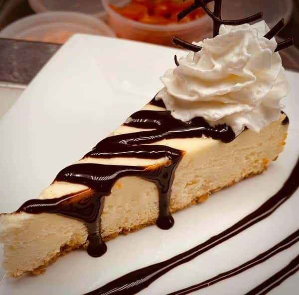 cheesecake topped with chocolate sauce and whipped cream