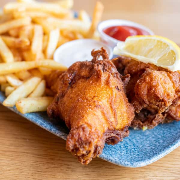 Crispy battered fish and golden chips served with lemon wedges and dipping sauces