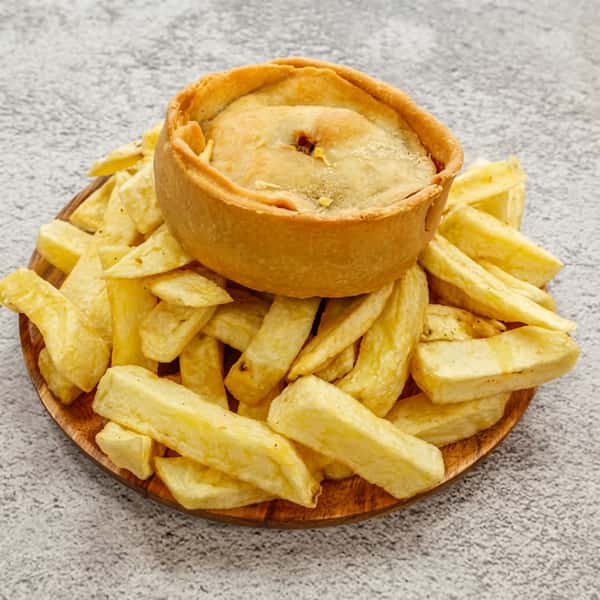 Golden savory pie served with thick-cut chips on a wooden plate