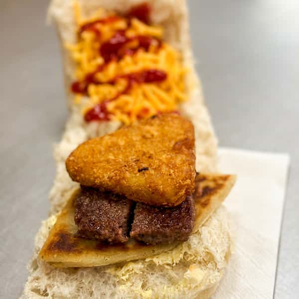 Steak sandwich topped with a crispy hash brown, served with chips and ketchup