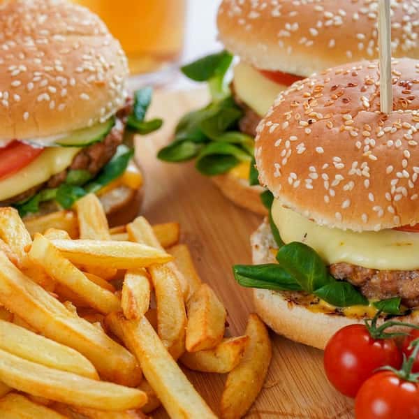 Cheeseburgers with fresh greens and tomato on sesame buns served with crispy golden French fries