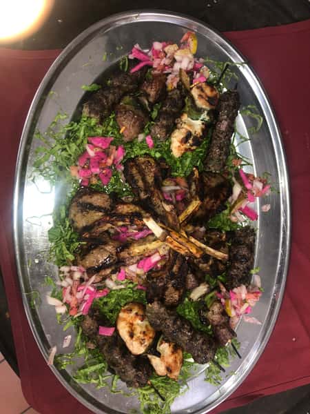 Mixed grill platter with grilled lamb chops, vegetables, and fresh herbs.