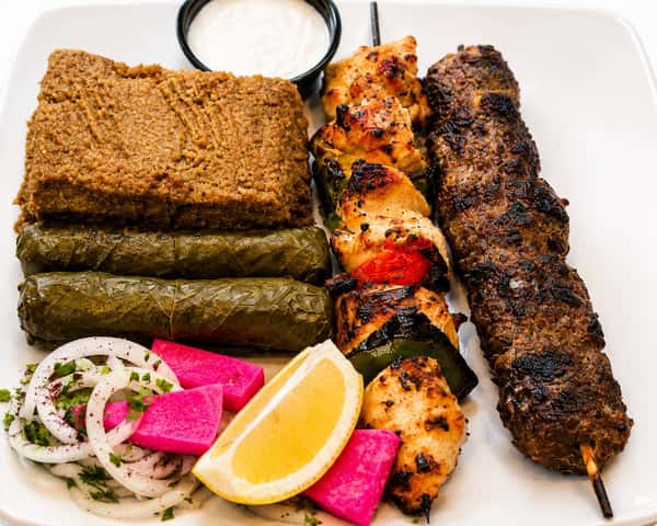 Mediterranean combination platter with kibbeh, stuffed grape leaves, chicken kebab, kafta, salad, and pickled turnips