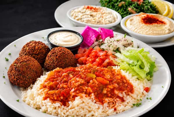 Falafel platter served with rice, tomato sauce, salad, hummus, yogurt sauce, and pickled turnips