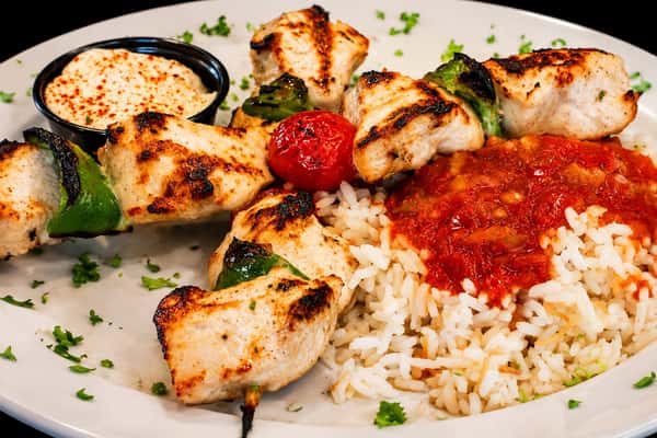 Grilled chicken kebabs with vegetables served with rice, tomato sauce, and garlic dip