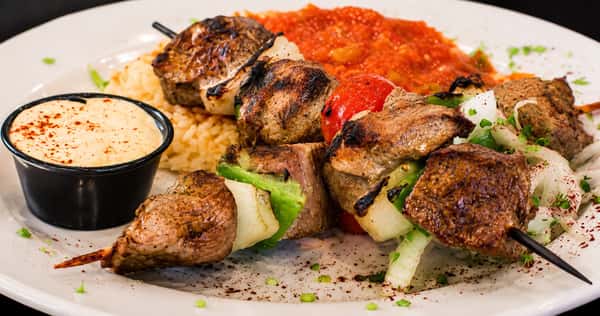 Grilled beef and lamb kebabs served with rice, tomato sauce, onions, and dipping sauces
