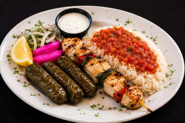 Chicken kebab and stuffed grape leaves served with rice, tomato sauce, onions, and garlic dip