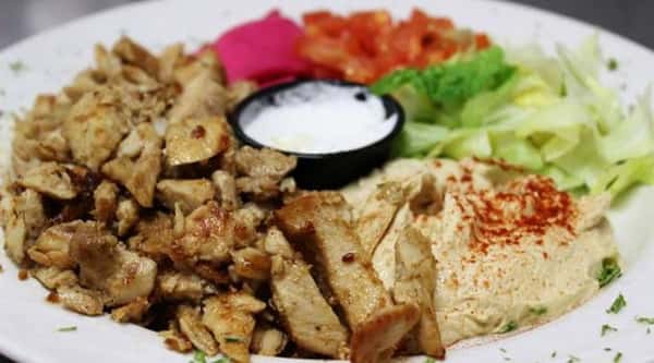 Chicken shawarma platter served with hummus, salad, rice, pickled turnips, and garlic sauce