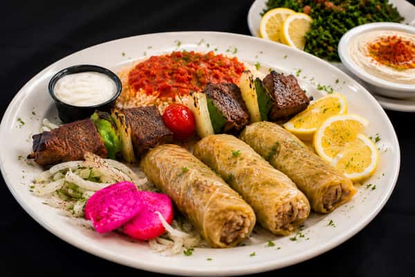 Mediterranean combination platter with stuffed cabbage rolls, grilled kebabs, rice, pickled turnips, and sauces
