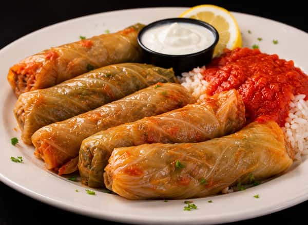 Vegetarian stuffed cabbage rolls served with tomato sauce, rice, and sour cream