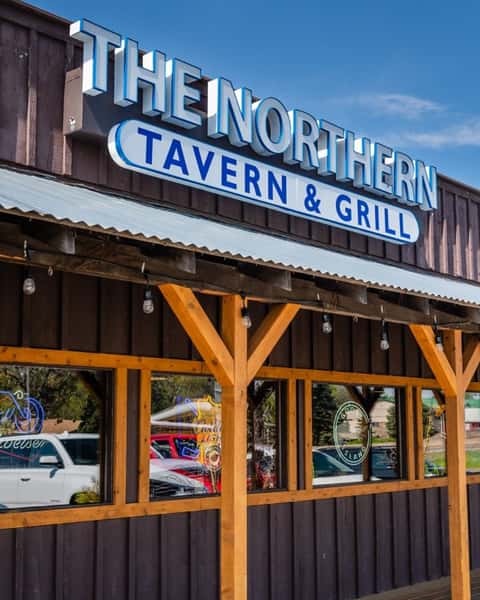 The exterior front entrance with a sign that reads "The Northern Lake Tavern & Grill"