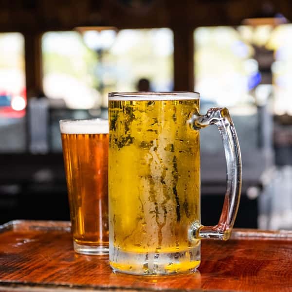 A glass and a mug of beer on the bar countertop