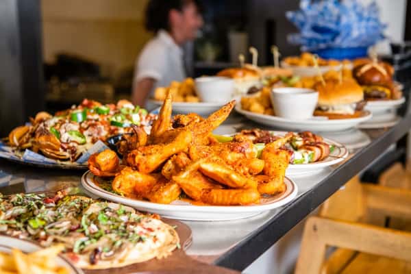 Multiple plates filled with different menu items such as fried fish, flatbread pizzas and burgers