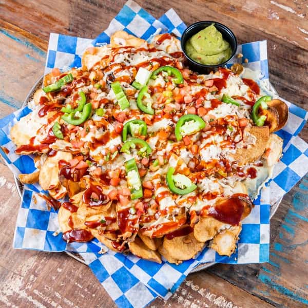 A nacho platter toped with jalapeno and BBQ sauce