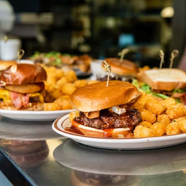Multiple plates filled with different menu items such as fried fish, flatbread pizzas and burgers
