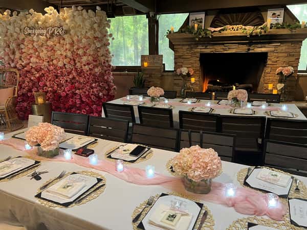 Floral-themed bridal shower with pink hydrangea centerpieces, votive candles, and a rose flower wall backdrop.