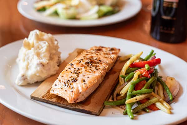 Cedar plank grilled salmon with cracked pepper, served with mashed potatoes and sautéed mixed vegetables.
