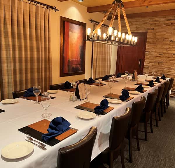 Elegant private dining room with white tablecloths, navy napkins, and warm ambient lighting.