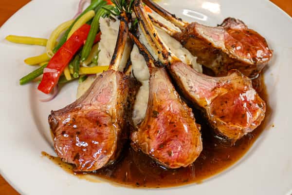 Glazed rack of lamb with rosemary demi-glace, served over mashed potatoes with sautéed mixed vegetables.