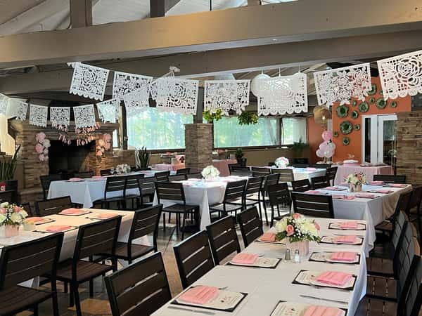 Festive shower celebration with pink floral centerpieces, papel picado banners, and soft pastel accents.
