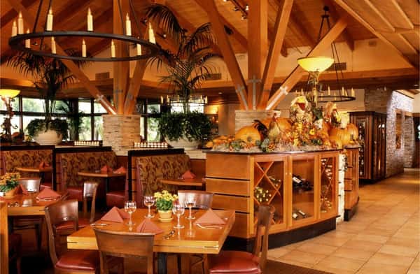 Warm, rustic upscale dining room with wood-beamed ceilings, elegant booths, and festive seasonal decor.