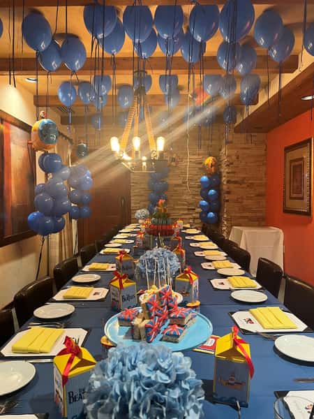 Party setup with blue balloons, themed decor, and a long table filled with treats and party favors.