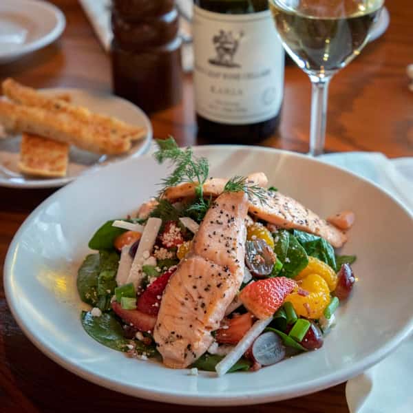 A fresh and colorful salmon salad featuring grilled salmon over mixed greens, tomatoes, cucumbers, and other garden vegetables. Lightly dressed and beautifully plated, it's a healthy and refreshing option ideal for a light yet satisfying meal.