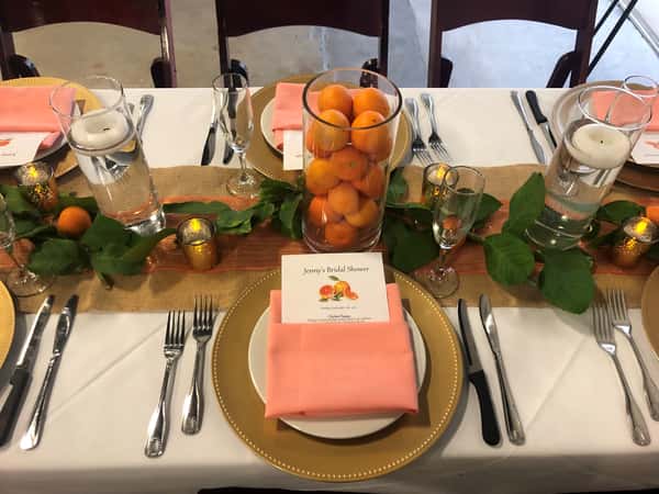 Peach-themed bridal shower table with apricot centerpiece and pink napkins.