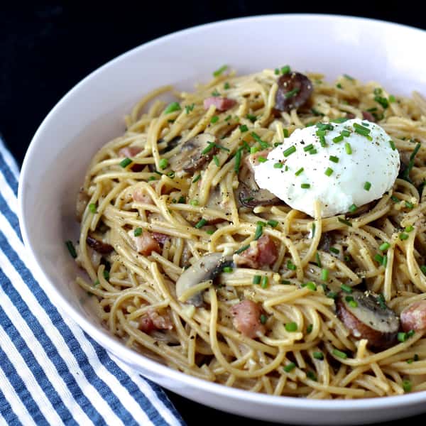 A comforting bowl of pasta tossed with vegetables and shredded meat, topped with a dollop of creamy ricotta cheese and a sprinkle of fresh herbs.