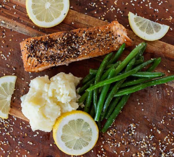 A perfectly seasoned grilled salmon fillet served with creamy mashed potatoes, crisp green beans, and fresh lemon wedges.