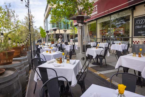 Outdoor patio dining at an Italian restaurant with white tablecloth seating