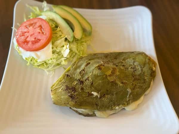 Grilled stuffed nopales (cactus paddles) served with a side of Mexican rice, shredded lettuce, sour cream, tomato slices, and avocado.